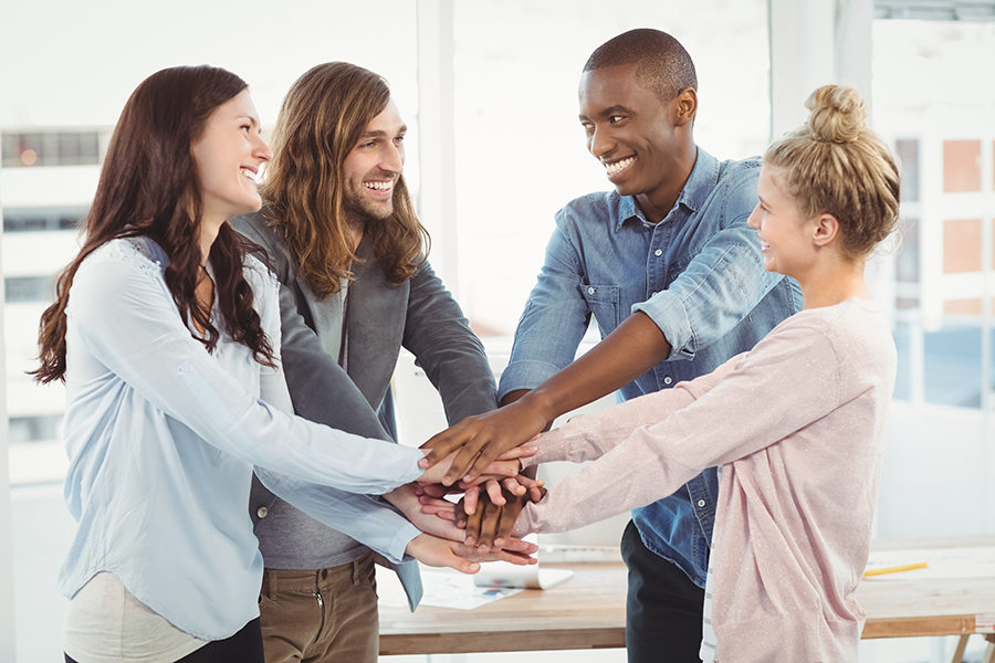 Smiling business team putting their hands together